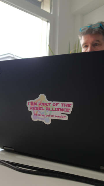 Backside of a laptop with a sticker saying "I am part of the rebel alliance" and the hashtag #FediverseFor Freedom