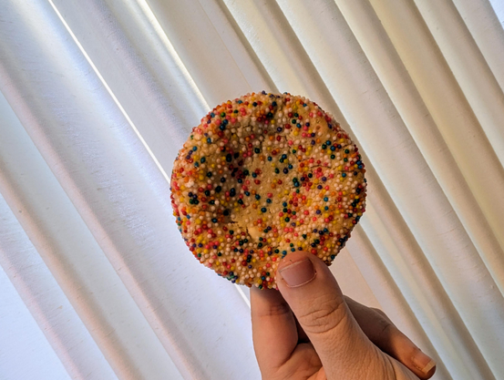 Holding up a cookie with birthday sprinkles