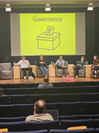 Panelists, in front of a drawing of a ballot box"