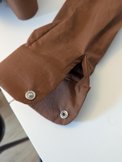 a shirt cuff with the type of fastening that's made from two metal parts, one with a hole and one with a sticking-up nub, which you squeeze together to join with a click, and pull apart to separate