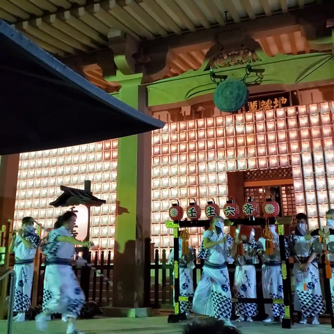 Musicians and dancers perform the frenetic 'Rokusai Nenbutsu' at Mibu-dera. The dancer tosses streamers into the crowd and prances with a fan and baton.