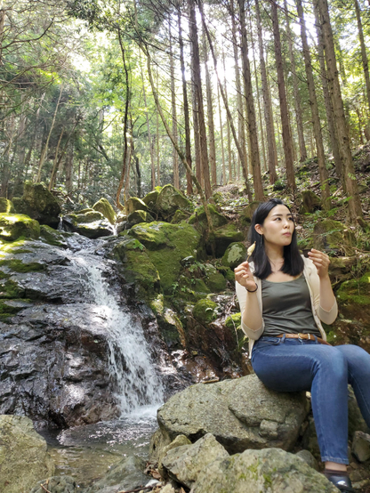 Nao-san eats snacks beside the Otowa-no-taki waterfall.