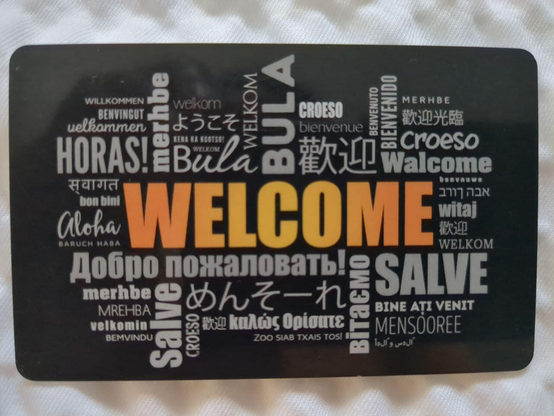 Welcome card at a hotel that has "Welcome" in many languages, including Okinawan in Japanese phonetic script.