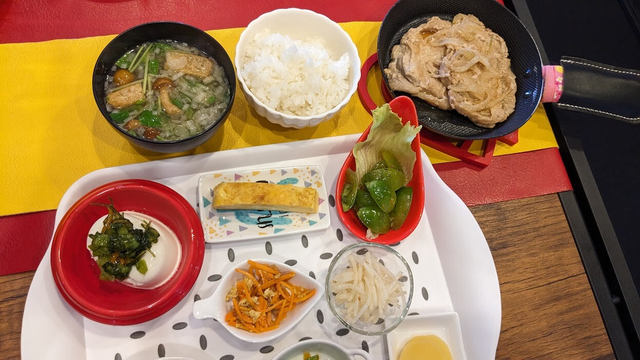 メインは豚肉の生姜焼き。御飯と御味噌汁と小鉢８種類が付くランチ定食というものです。御味噌汁にはなめこと揚げと三つ葉と揚げ玉が入ってました。小鉢は左上から冷ややっこに山葵味の何かが入った昆布や漬物を和えたものが載せてありました。上の真ん中は出汁焼き卵。右上が青いミニトマトのマリネ。真ん中が卵の人参しりしり、真ん中右がちゃんと髭を取ってあるもやし炒め。