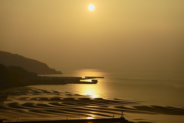The setting sun casts the sea and coast in fabulous oranges.