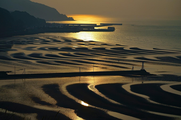 The setting sun casts the sea and coast in fabulous oranges.
