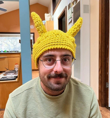 Me in a yellow crochet banana slug cap in my living room, smiling