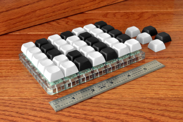 Five rows and seven columns of black and white keys on a circuit board. If you imagine the rows as guitar strings, the black and white caps are arranged in such a way that a keyboard player finds the black ones where they expect to find them (C and F having white, C# and Bb having black). So you can play the layout of a guitar and have the orientation given by the usual arrangement of black and white piano keys.