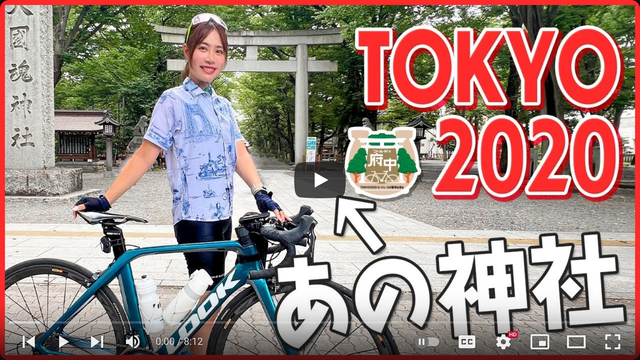 Screenshot of a youtube thumbnail with the words "Tokyo 2020" written in roman characters, and "あの神社" with an arrow pointing at a white torii gate in the background and a woman posing with a road bike in the foreground.