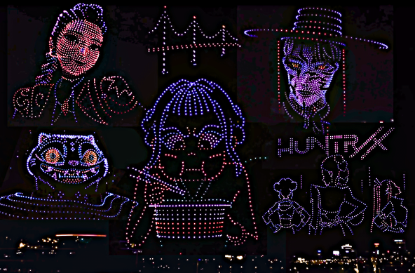 Illuminated drone formations against a dark night sky displaying various characters from KPop Demon Hunters, including character portraits and the "HUNTR/X" text logo, with city lights visible in the background below the aerial light show.