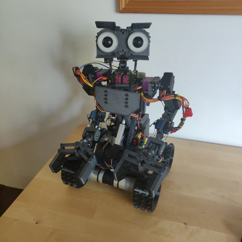 A small robot with two arms, four wheels, and a head with a pair of cameras for eyes