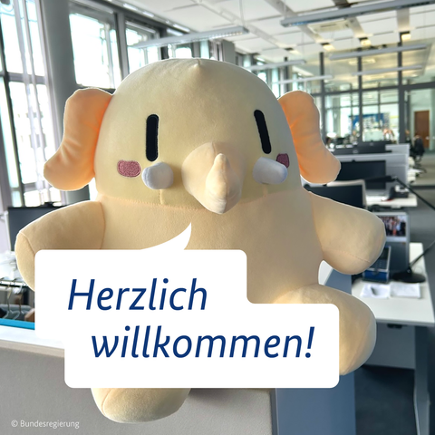Zentral im Bild ist das Mastodon-Maskottchen zu sehen. Darauf ist eine Sprechblase gesetzt, in der steht: Herzlich willkommen!