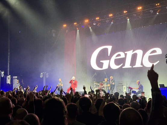 Gene on stage: man in red suit with "Gene" in background
