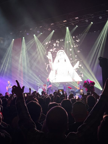 Band on stage playing Sleep Well Tonight with cover photo on screen