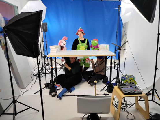 The same studio setup with my wife and our puppet characters in frame. You can see the puppeteers hiding under the table.