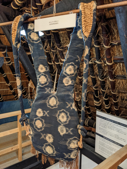 An early form of back support, designed for carrying loads such as bundles of wood. The material is dyed with indigo.