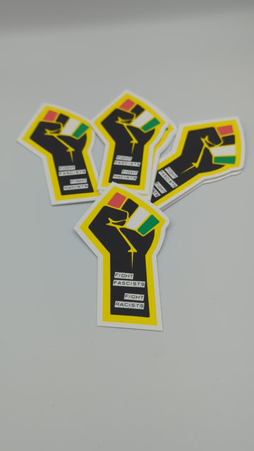 A photo of a sticker against a white backdrop - a vertical black fist with a yellow outline, fingers coloured red, black, white and green for the flag of Palestine. Down the wrist and arm are the words: fight fascists, and below: fight racists