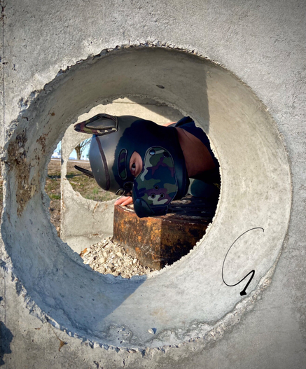 A human dog peeking though a concrete tube