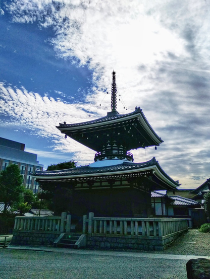 A two-storey pagoda contrasts with the backlit sky, blue with fuzzy clouds.