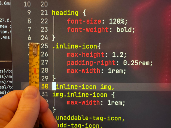 A photograph of a screen with a text editor. In front of it is a thumb holding a ruler with metric and imperial measurements. 

5 lines of text are just under two inches, or five centimeters tall.