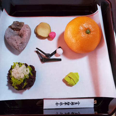 An orange is presented with other traditional sweets as part of a New Year temple meal.