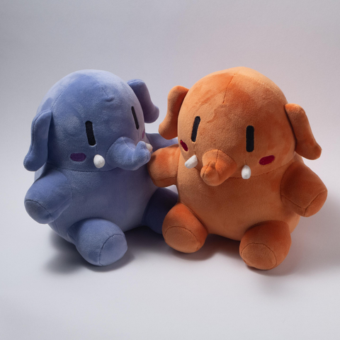 A blue and an apricot-colored Mastodon stuffed toy are sitting next to each other, looking small and cute (with rosy cheeks).