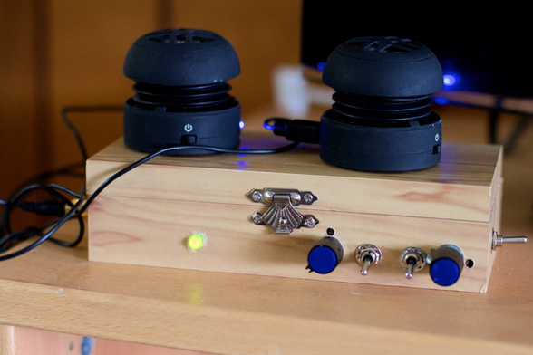 A small wood box with dials and swithes on the frpont, sitting on top are two hub shaped mysterious objects with cables. What does this box do?