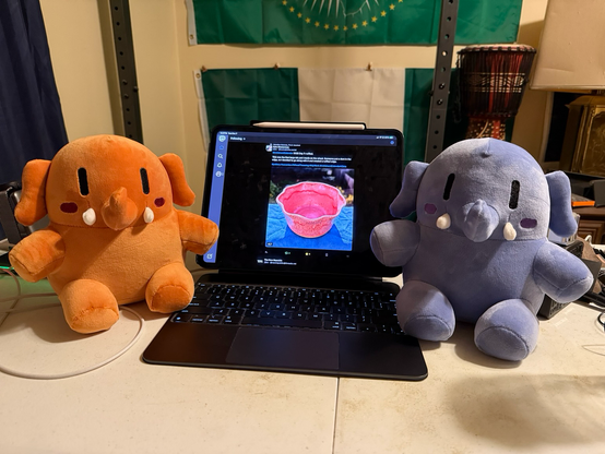 Two smaller plushies next to the iPad Pro in the center. iPad Pro is displaying the Mastodon app.