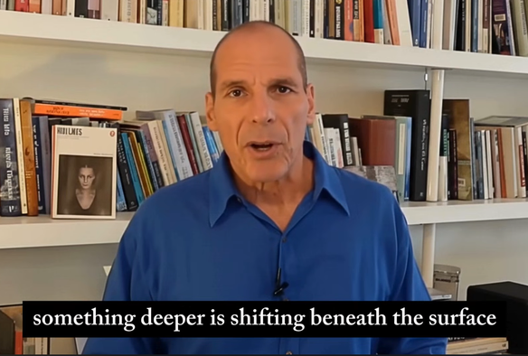 Screenshot from the video showing the Varoufakis AI surrogate talking in front of a book case, and just saying and shown in the subtitles "something deeper is shifting beneath the surface". Very appropriate, that.