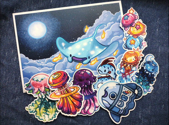 A print of a manta ray flying through the night surrounded by colorful jellyfish stickers and a mola astronaut