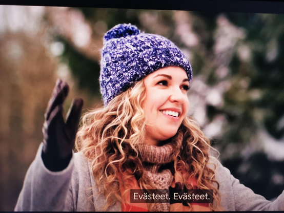 Kuva joululeffasta, jossa on leveästi hymyilevä nainen kädet levällään ja tekoälyn tekemä tekstitys "Evästeet. Evästeet.".