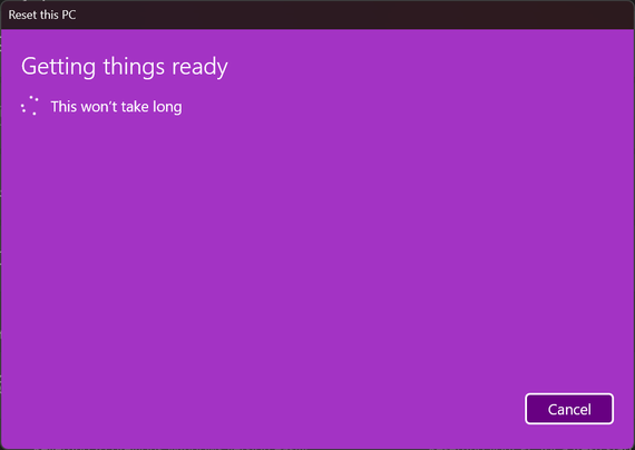A Windows computer screen displaying the “Reset this PC” interface with a purple background. The message reads “Getting things ready. This won't take long” with a loading hourglass icon. A “Cancel” button is visible in the bottom right corner.