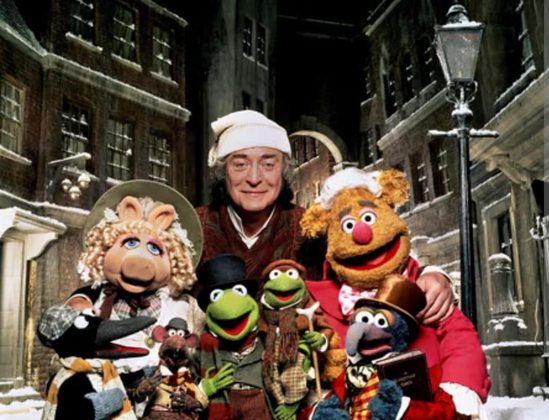 The cast of the Muppet Christmas Carol standing in invitation to watch together. We see Michael Caine and miss piggy, Kermit, tiny Tim, gonzo and a bear that has a name but I don't remember, plus the adorable rat and maybe a penguin (?) the scene is winter.