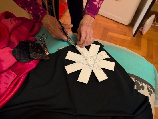 Grandma cutting a black cloth following the shape of the asterisk I previously cut on paper.