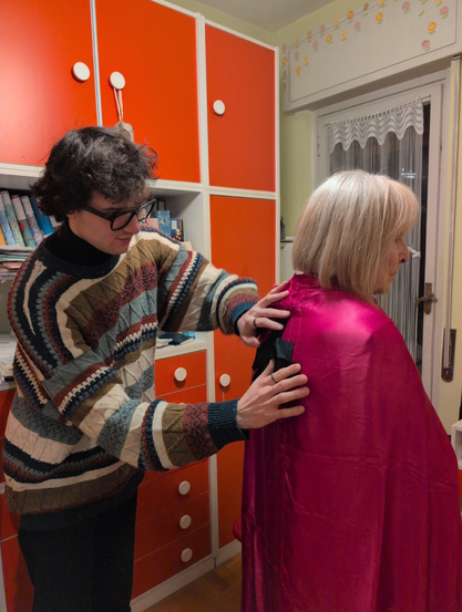 Photo of me while I position the topmost asterisk of the asterism on the back of the cape while Nonna D is wearing it.