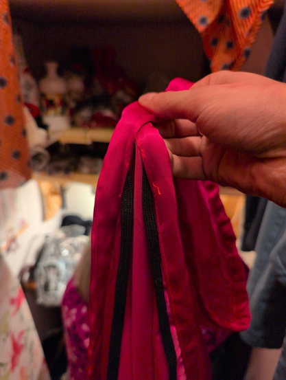 Black strings coming off of two holes in the topmost side of the cloth.