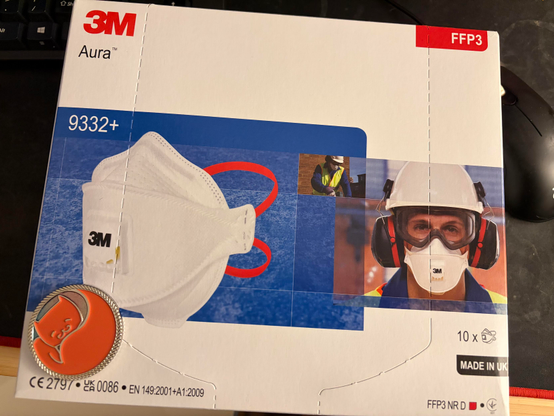 a box of 10 3M Aura 9332+ face respirators wrapped. in the bottom left corner is the .meow challenge coin from 39c3 