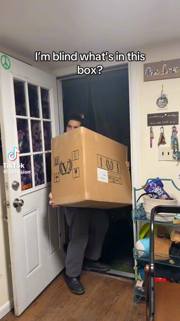 A white blind man with his brown hair in a bun. He is unboxing and testing his new guitar amp