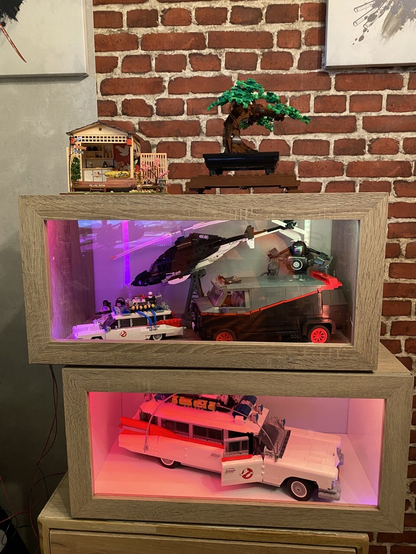 A showcase made of wood and plexiglass with a Lego Ecto-1 and a brick airwolf and a-Team van. 