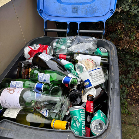 Recycling bin full to the brim with bottles and cans from last night's party