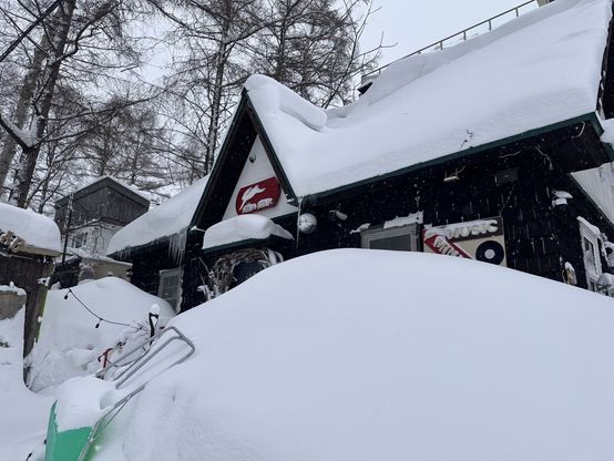 The front of a restaurant in Grand Hirafu mostly obscured by a large drift of powder snow.