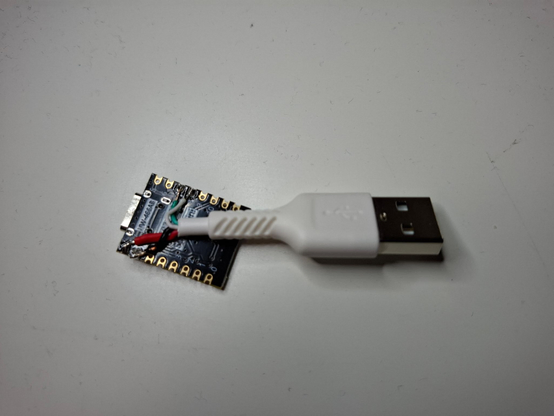 An ESP32C3 microcontroller with wires soldered to it coming out of a cut off USB cabel, where the other end is USB A