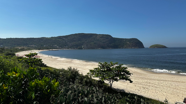Picture of Camboinhas Beach in Brazil. White sands, light surf, blue water, surrounded by vegetation