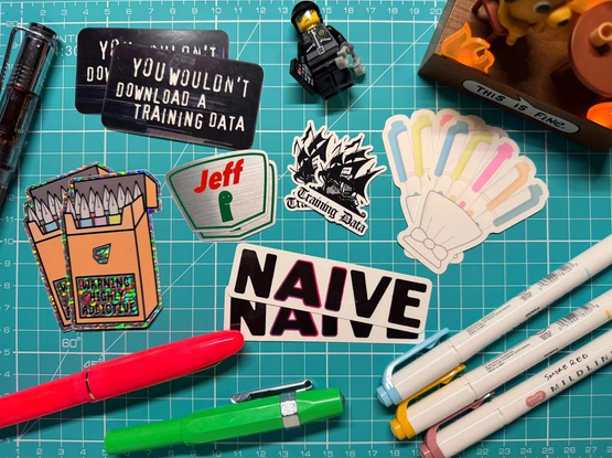 A load of stickers on a cutting board. Some are about pens, some are about AI, there are also other items like pens surrounding them. 