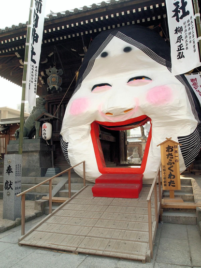 Visitors pass through the mouth of a giant Otafuku mask at Kushida-jinja in Fukuoka during Setsubun celebrations.