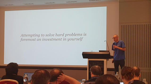 Daniel Gustaffson in his talk showing a slide saying "attempting to solve hard problems is foremost an investment in yourself".