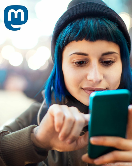Frau tippt auf ihrem Handy, ein Mastodon-Logo ist zu sehen. 