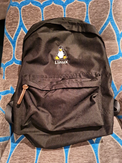 Black backpack with Tux, the Linux penguin logo, embroidered on it and ‘Linux’ embroidered underneath.