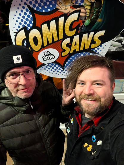 Allan and Cassidy standing in front of a “Comic Sans” sign