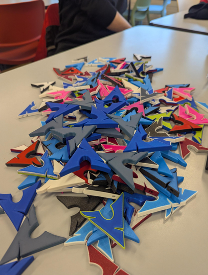 Picture of a table with a lot of 3D printed Arch Linux keychains on top.